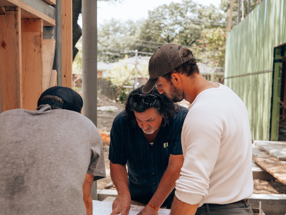 Builders reviewing plans together at a timber-framed residential build site
